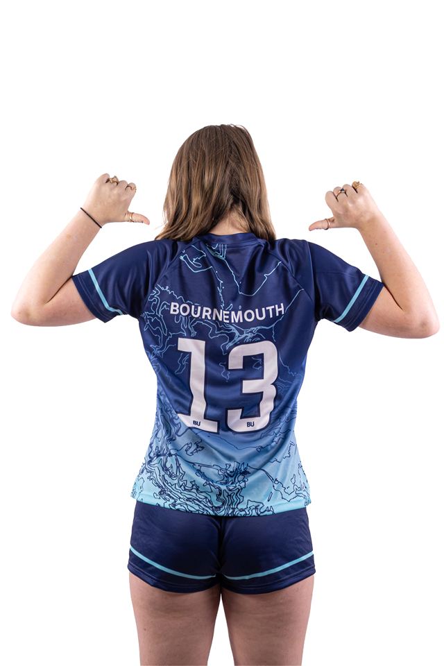 A player turned away from the camera, pointing at the number 13 on her shirt