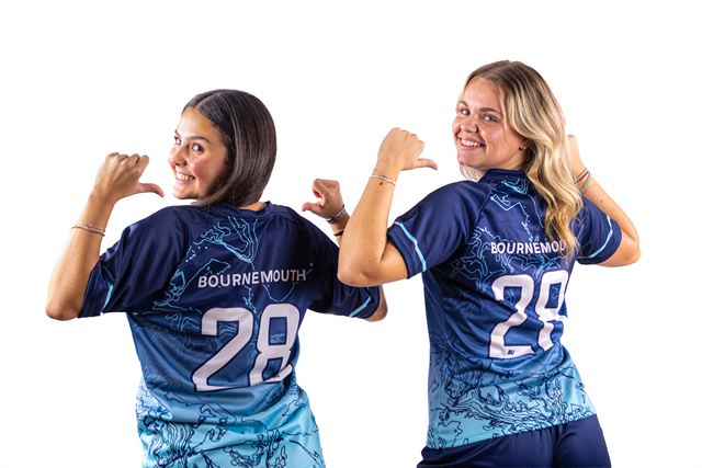 Two players pointing over their shoulders at the names on their shirts