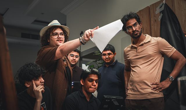 Cast and crew gathered round as someone holds up a sheet of paper