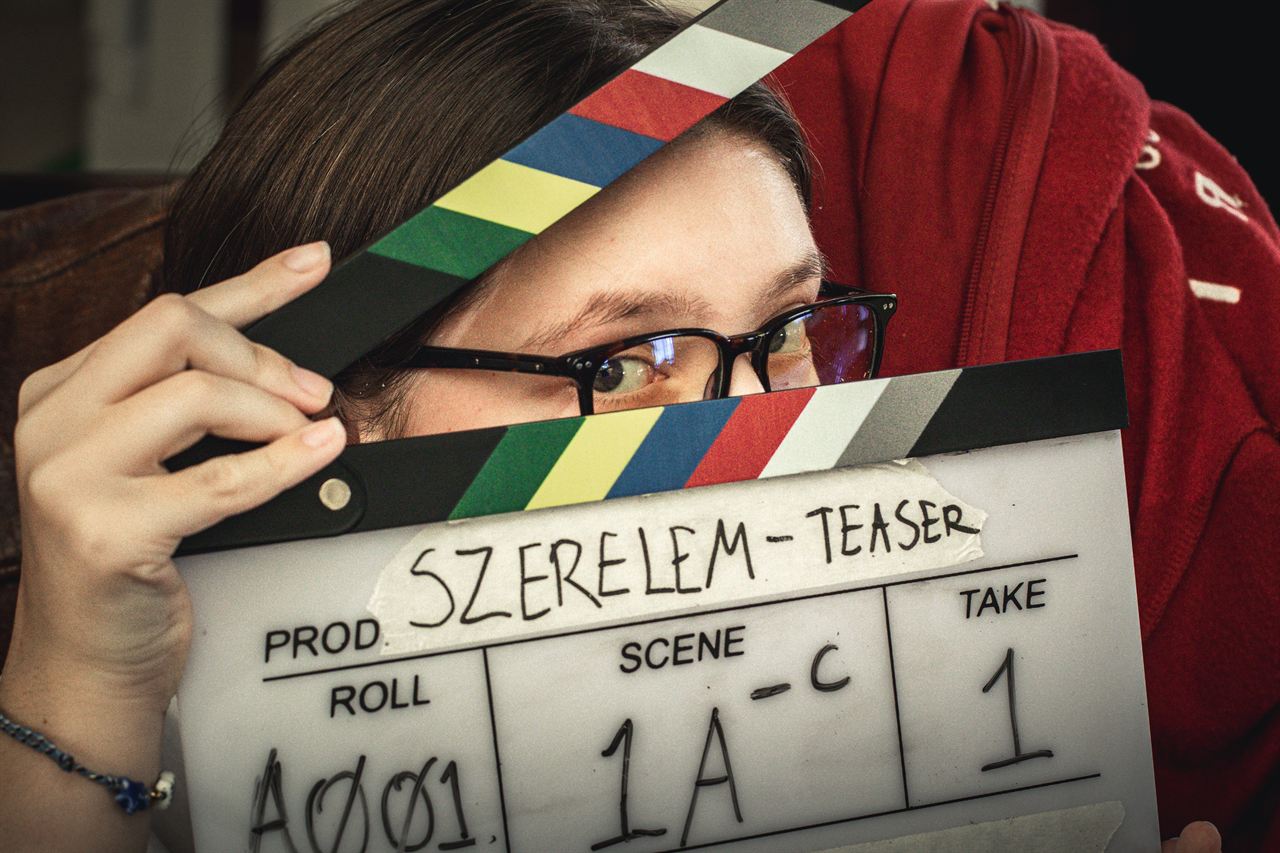 An actor peeking over a clapperboard on a short film set